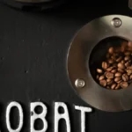 Close-up of a person performing preventive maintenance on an industrial coffee roasting machine drum.