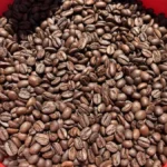Roasted coffee beans pouring into a ceramic bowl with warm atmospheric lighting.