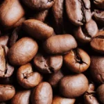 Two different varieties of roasted coffee beans showing contrasting colors and textures.