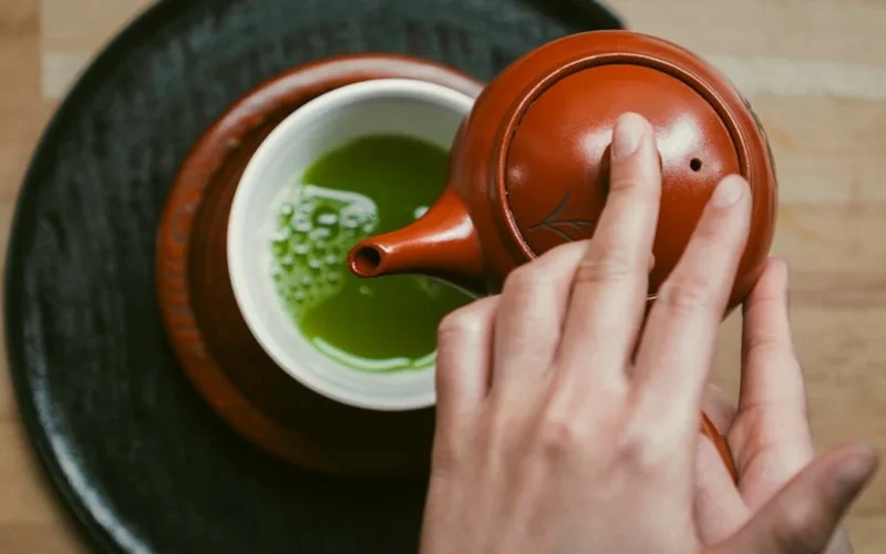A minimalist tea ceremony setup with matcha bowl and bamboo whisk in soft natural light.