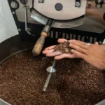 High-tech coffee roaster display showing real-time data and control interface surrounded by coffee beans and paper.