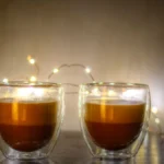 Close-up of fresh espresso pouring into a glass cup with thick golden crema.