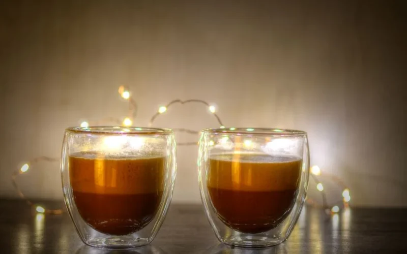 Close-up of fresh espresso pouring into a glass cup with thick golden crema.