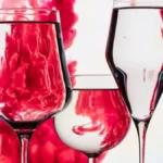 A chilled glass of red wine with condensation droplets on dark marble.