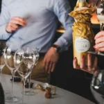 A bottle of premium sparkling wine and two filled crystal flutes on ice.