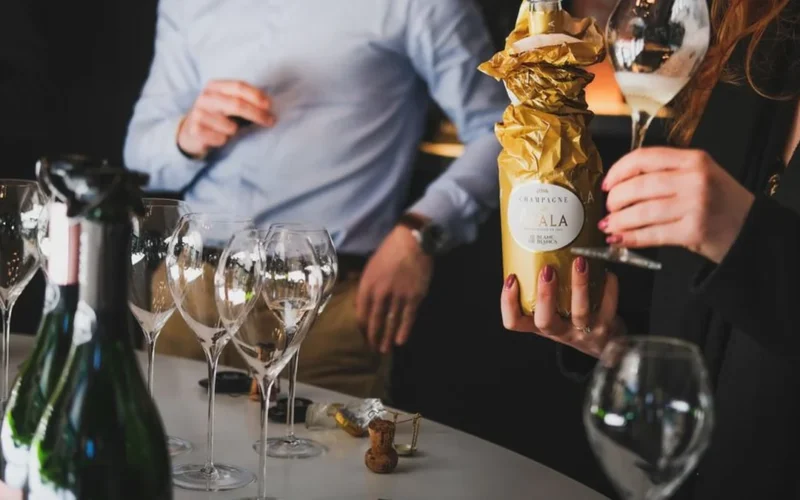 A bottle of premium sparkling wine and two filled crystal flutes on ice.