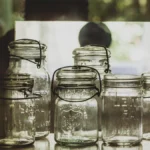 Various glass jars filled with different colored kombucha and loose tea leaves.