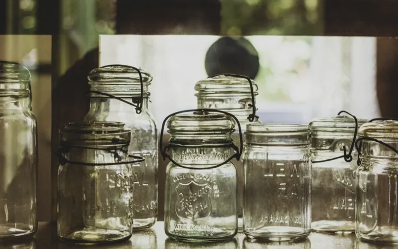 Various glass jars filled with different colored kombucha and loose tea leaves.