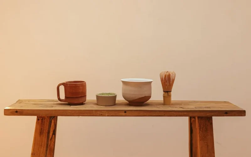 A traditional tea ceremony with matcha powder being poured into a bowl, surrounded by bamboo and fresh tea leaves.