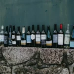 Wine bottles sitting beside stacks of administrative paperwork and official documents on a bar.