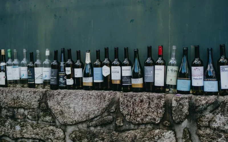 Wine bottles sitting beside stacks of administrative paperwork and official documents on a bar.