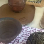 Tea leaves flip on gaiwan lid with steam rising in soft golden light.