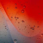 Close up of red wine swirling in a glass with water droplets on marble.