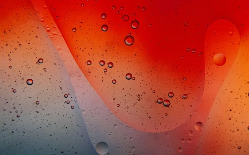 Close up of red wine swirling in a glass with water droplets on marble.