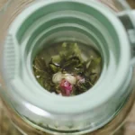 Dark aged puer tea leaves unfurling in a clay teapot with rising steam under warm lighting.