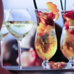 A glass of red Pinot Noir and a glass of orange wine on a wooden table.