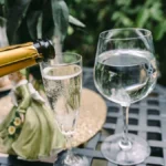 A chilled bottle of Bollinger Blanc de Noirs Champagne and a sparkling flute on wood.
