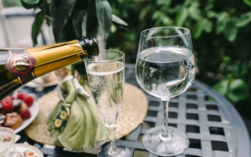 A chilled bottle of Bollinger Blanc de Noirs Champagne and a sparkling flute on wood.
