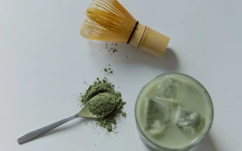 Layered iced matcha latte with botanical garnishes on a marble cafe table.