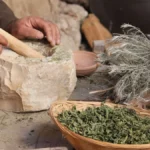 Close-up of traditional stone mill grinding fresh green matcha powder on a wooden surface.