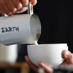 Hands using a silver spoon to taste coffee during a sensory cupping session.