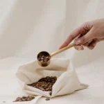 Person holding both raw green and roasted brown coffee beans in their palms.