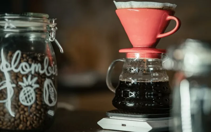 Three clear glass carafes of brewed coffee arranged next to small single origin coffee bean bags.