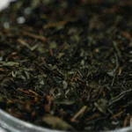 Compressed dark Fu zhuan tea cake and amber brewed tea in a ceramic cup.