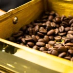 Roasted specialty coffee beans near a Chemex brewer and professional roasting tools.