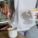 Pouring hot water into a Clever Dripper sitting on a glass carafe for large batch brewing.