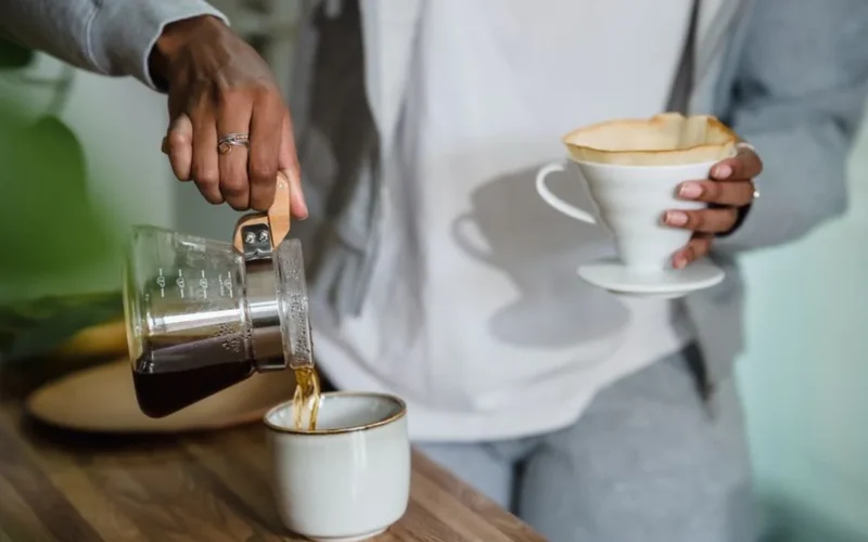 Pouring hot water into a Clever Dripper sitting on a glass carafe for large batch brewing.