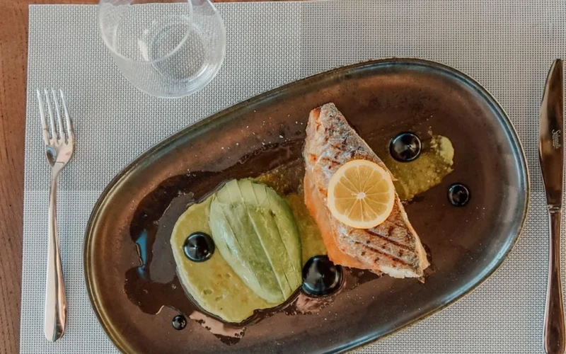Close up of a seafood dish and a glass of white wine on a dining table.