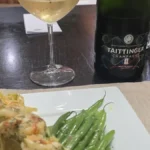 A glass of sparkling Taittinger Champagne with fine bubbles next to seafood.