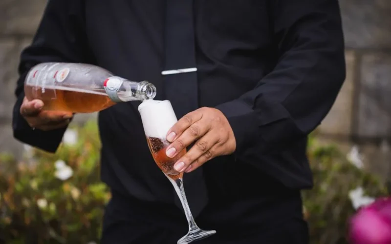 A sparkling wine flute beside an amber digestif in a crystal glass on marble.
