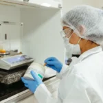 Scientist inspecting raw green coffee beans in a university research laboratory setting.