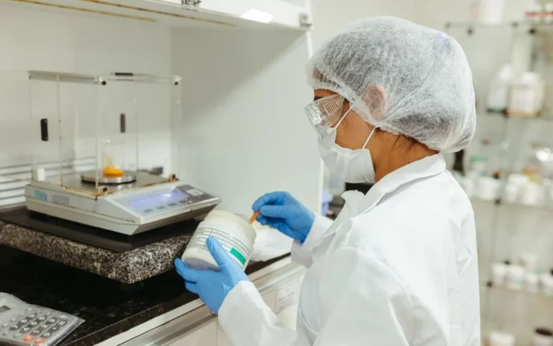 Scientist inspecting raw green coffee beans in a university research laboratory setting.