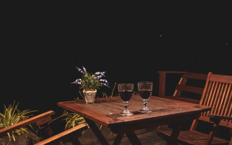 A bottle of Côte Rotie red wine and a filled glass on a wooden table.