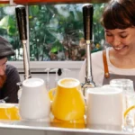 Two female baristas preparing coffee drinks inside a modern neighborhood coffee shop.