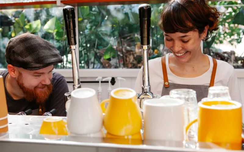 Two female baristas preparing coffee drinks inside a modern neighborhood coffee shop.