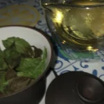 Fresh green spearmint leaves submerged in a clear glass cup with small air bubbles.