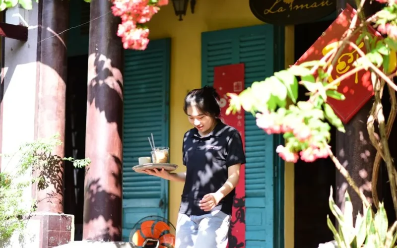 A professional barista serving a latte to a customer in a specialty coffee shop setting.