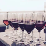 Three wine glasses filled with varying shades of pink rosé wine on a stone surface.