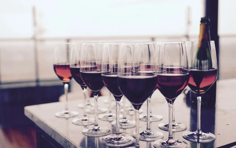 Three wine glasses filled with varying shades of pink rosé wine on a stone surface.