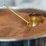 Spiced Yemeni coffee served in an ornate cup with cardamom pods on marble.
