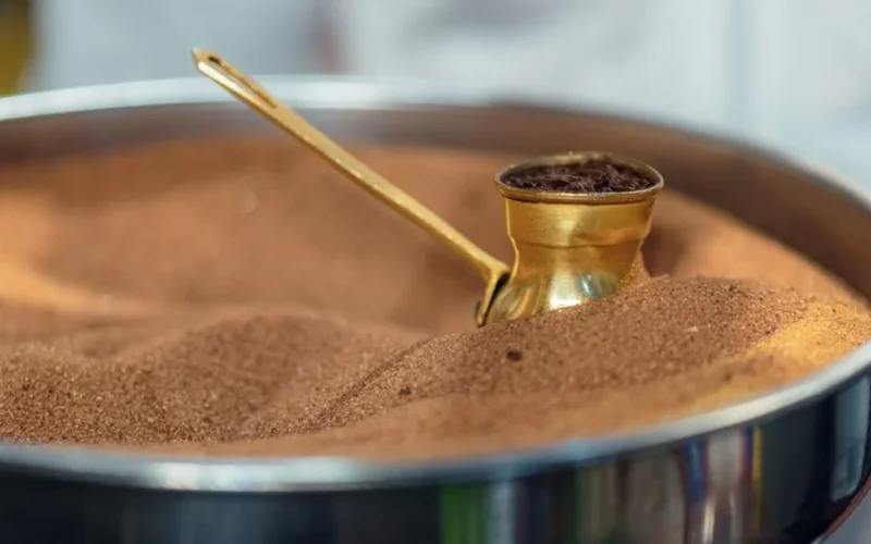 Spiced Yemeni coffee served in an ornate cup with cardamom pods on marble.
