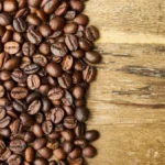 A variety of different specialty coffee bean types scattered on a dark textured surface.