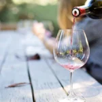 Opus One wine bottle and crystal glasses filled with Cabernet Sauvignon on a wooden table.