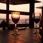 A single glass of red wine on a dark wooden table in low light.