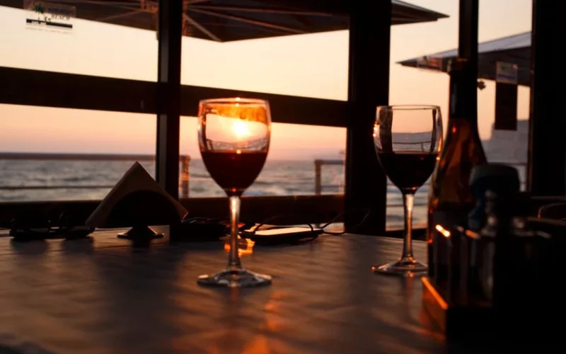 A single glass of red wine on a dark wooden table in low light.