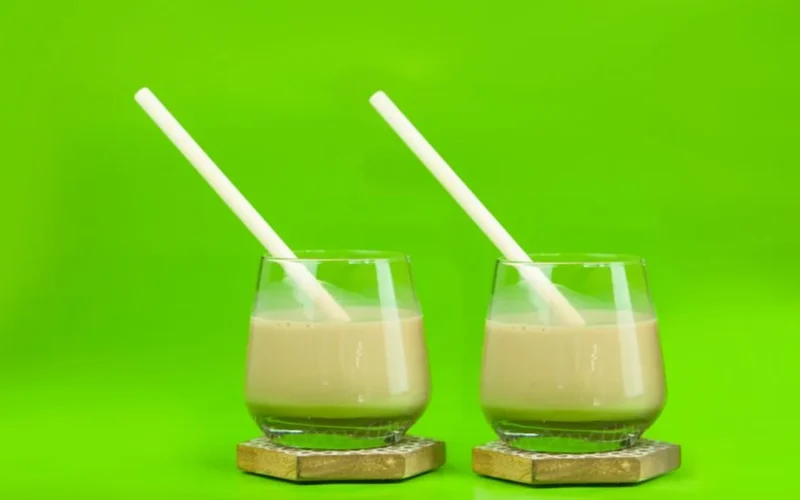Cold brew coffee with milk swirling around ice cubes in a tall glass.